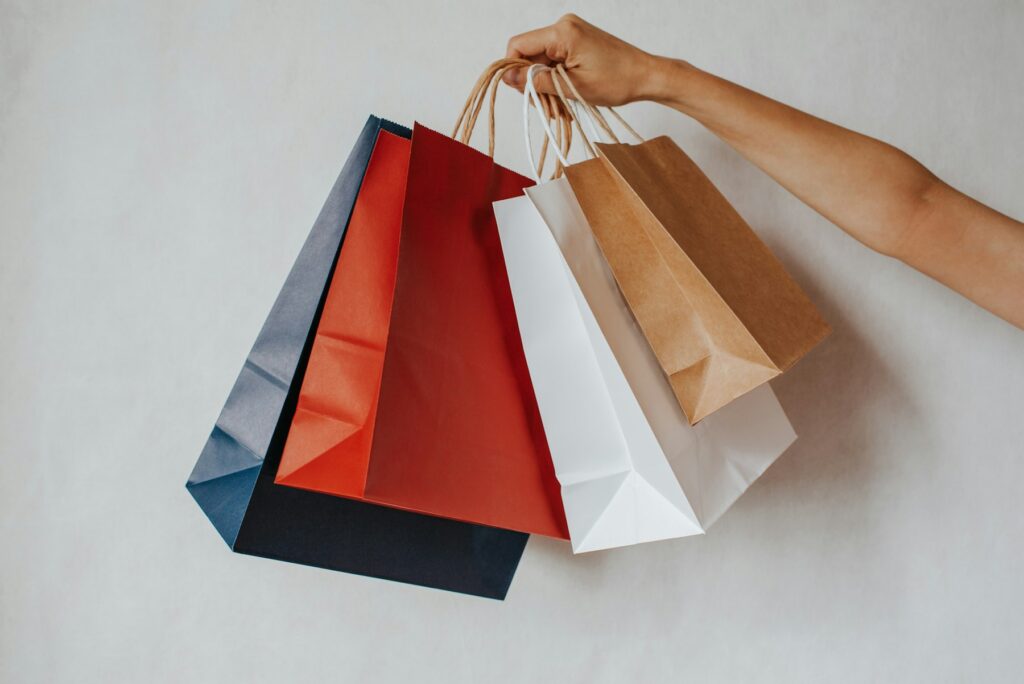 Hand holding colorful shopping bags against a white background