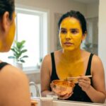 Woman applying a golden turmeric (haldi) face pack in the mirror